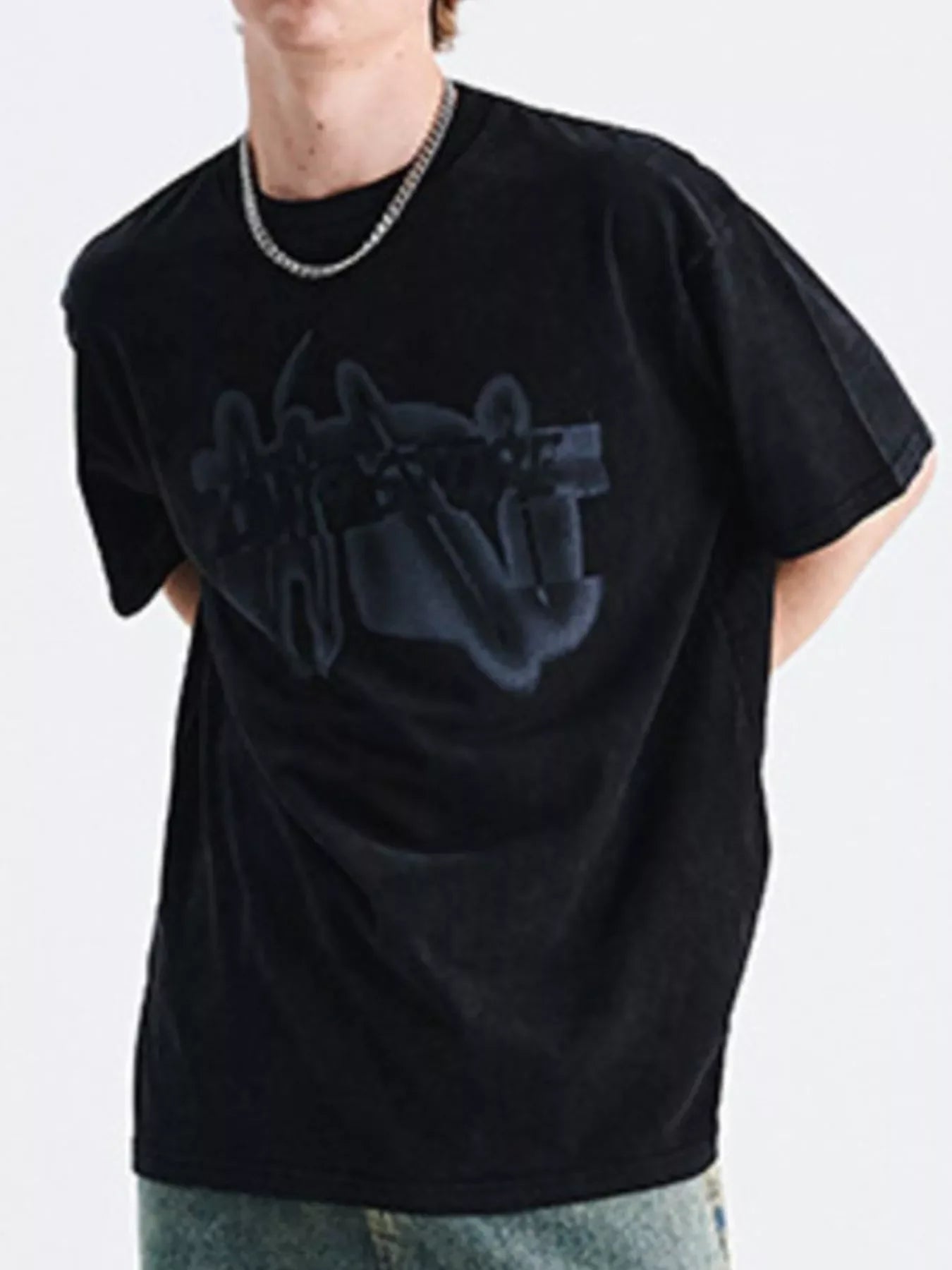 Man wearing oversized black streetwear t-shirt with abstract graphic, blue jeans