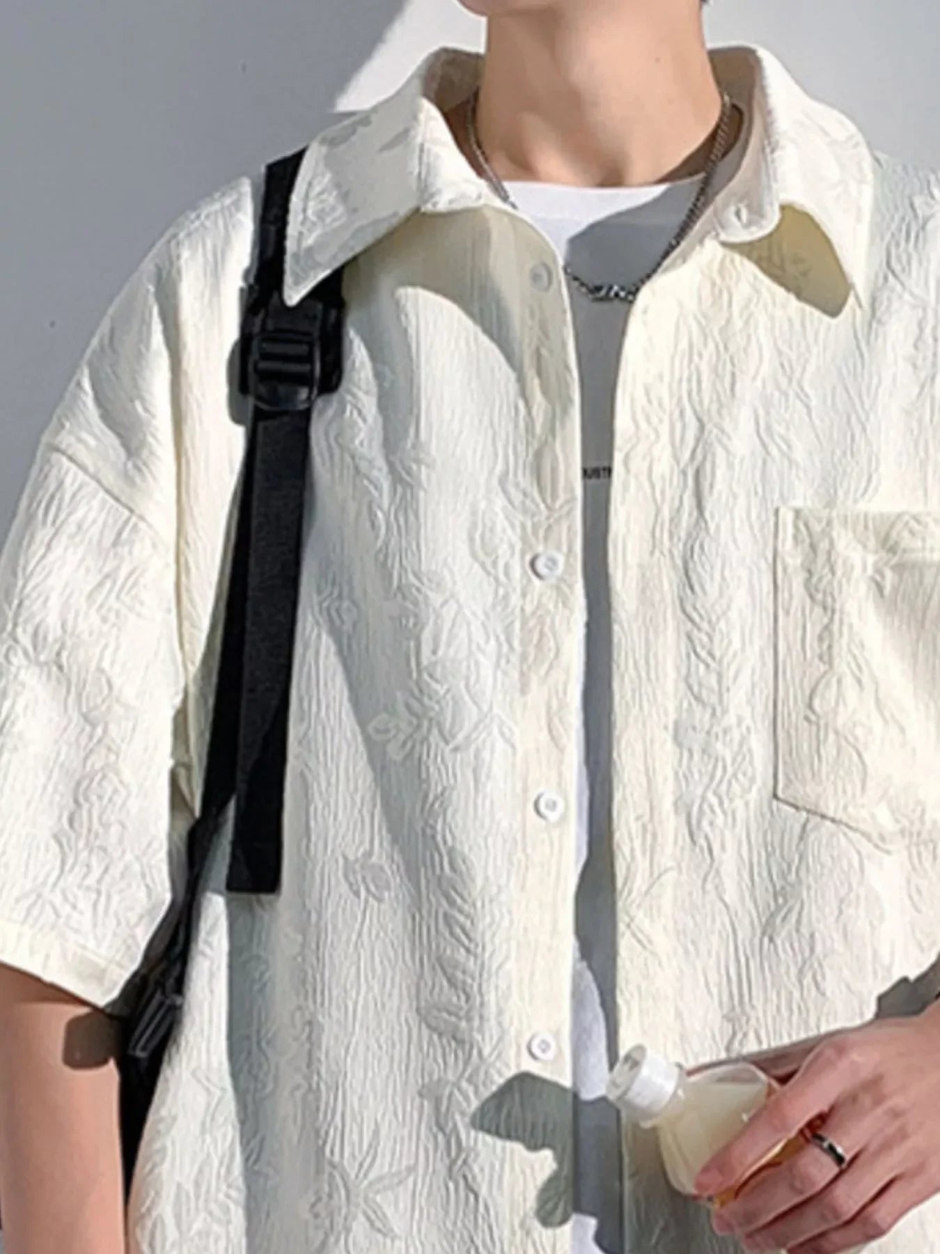 Man wearing textured white streetwear shirt with floral pattern and white t-shirt underneath