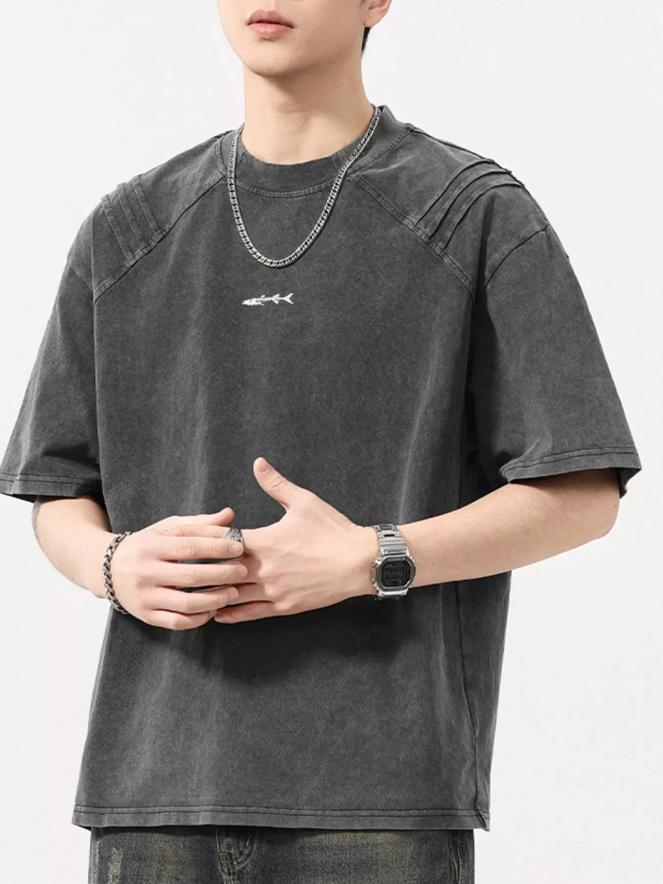 Man wearing oversized washed black streetwear t-shirt with small fish graphic, urban style