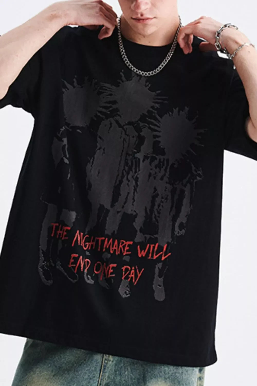 Man wearing oversized black streetwear t-shirt with bold graphic and red text design.