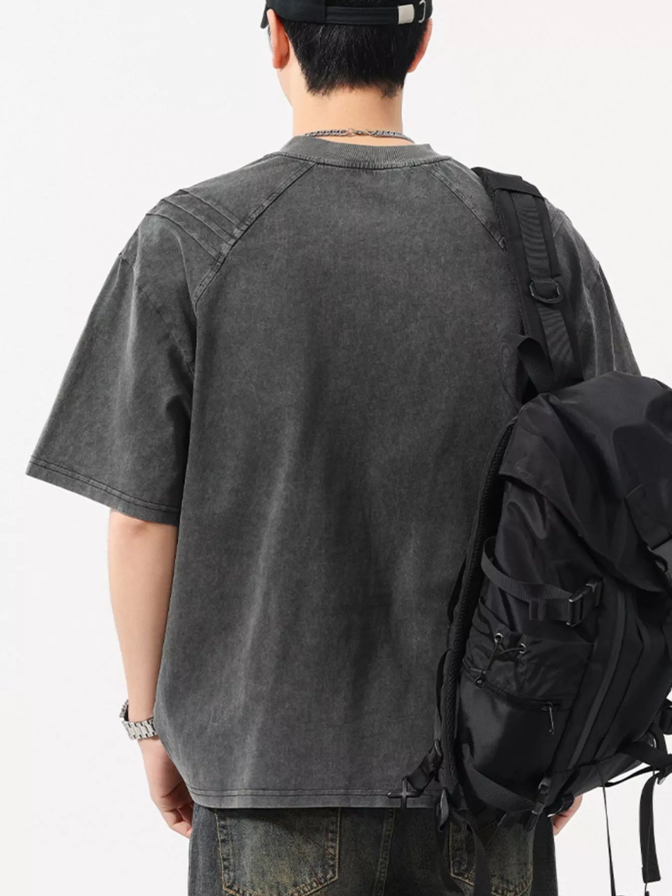 Man wearing oversized black washed t-shirt, streetwear jeans, and black backpack