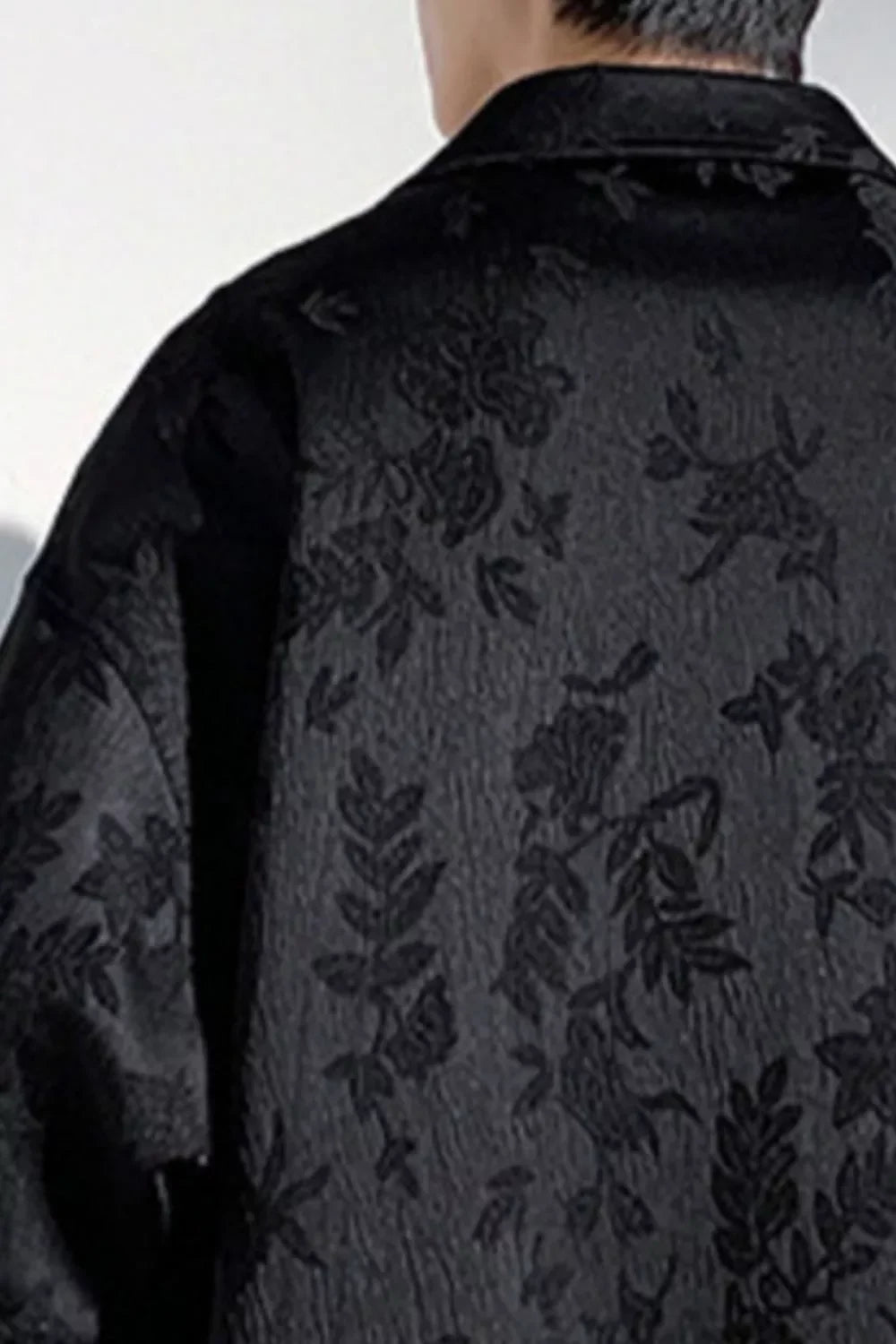 Close-up of a man's black jacquard streetwear shirt with subtle floral pattern