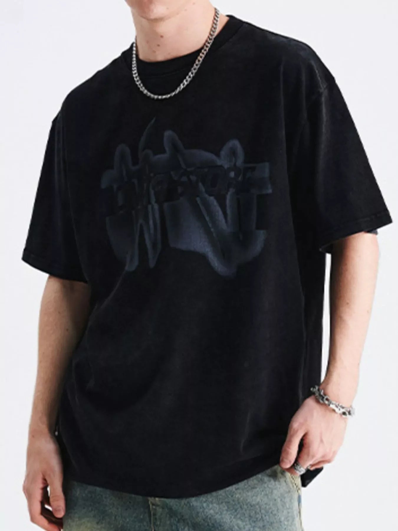 Man wearing oversized black streetwear t-shirt with graphic print and chain accessories