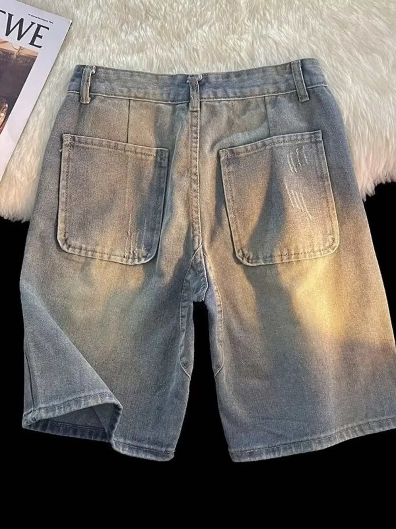 Back view of light wash denim shorts with large back pockets, urban streetwear style