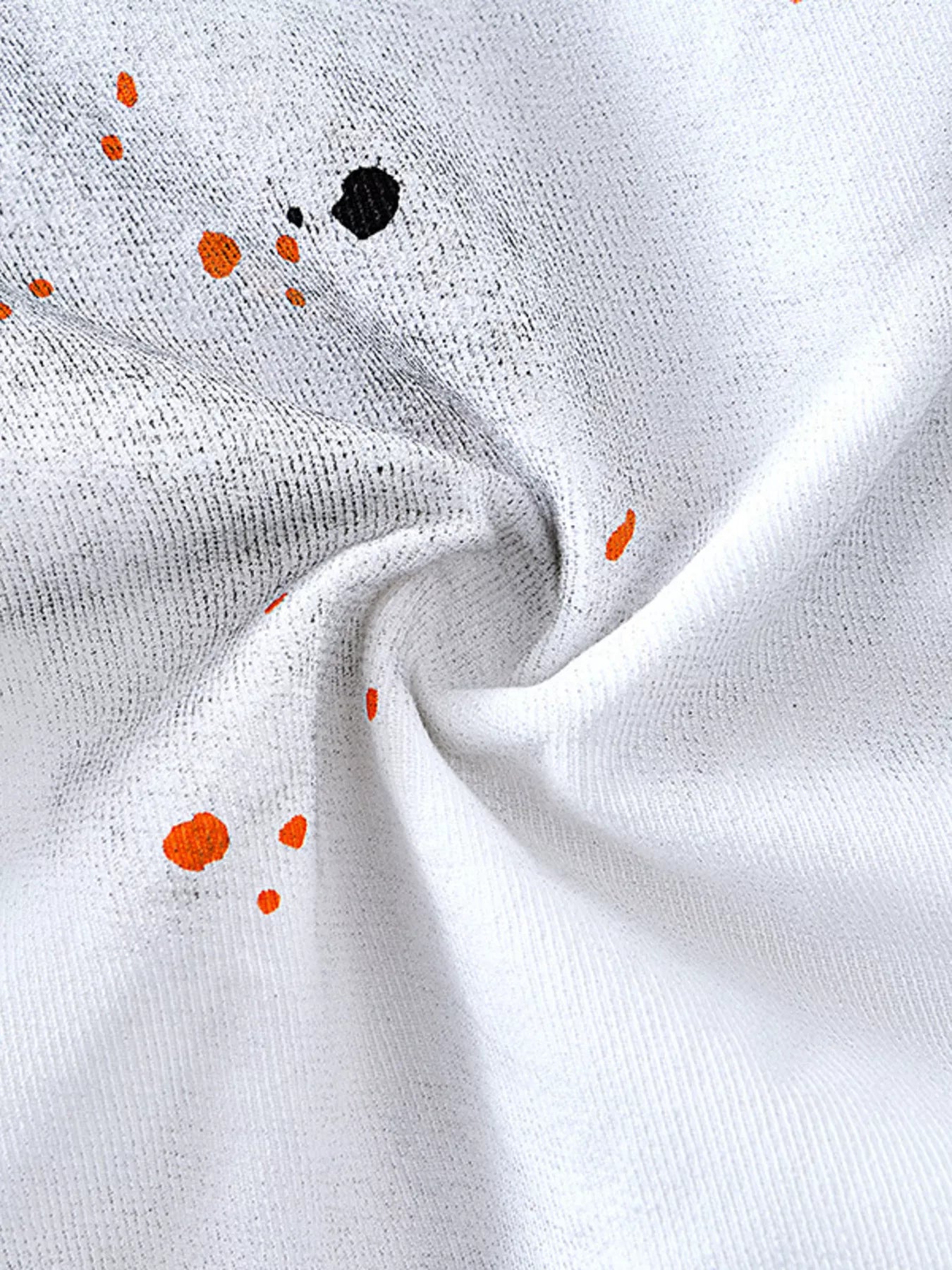 White streetwear fabric with orange and black paint splatter graphic detail, close-up texture