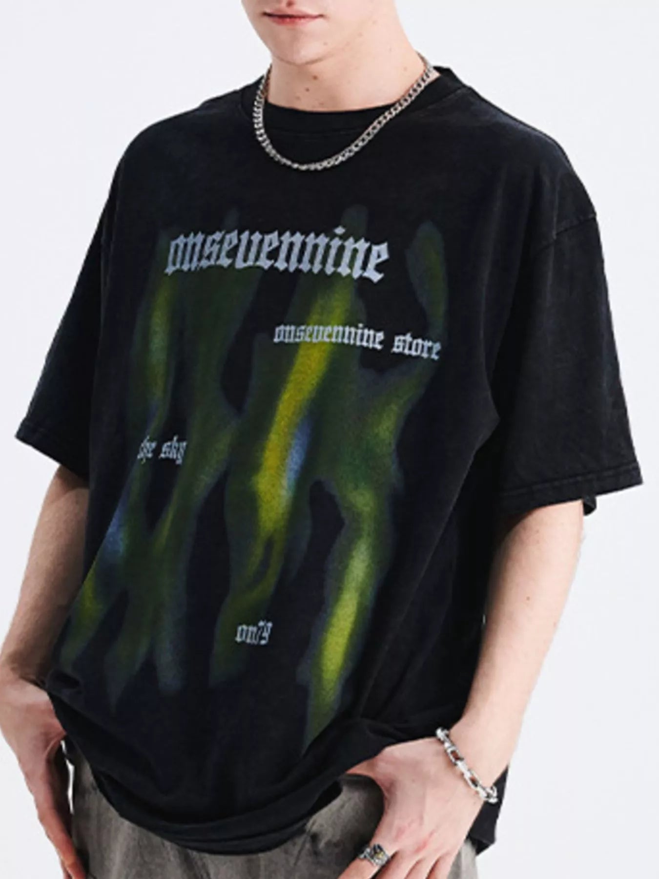 Man wearing oversized black streetwear t-shirt with abstract green and blue graffiti print