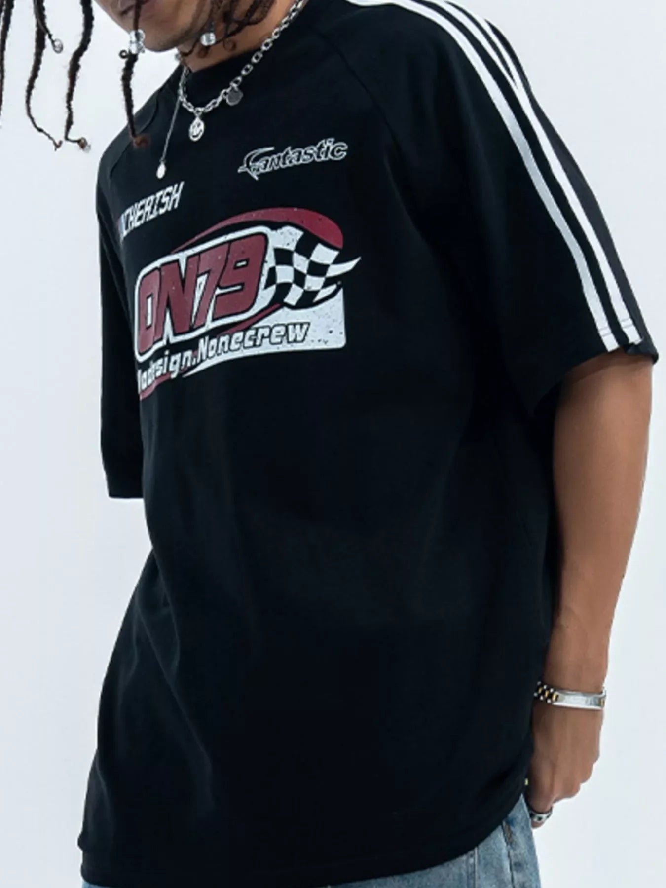 Man wearing oversized black graphic streetwear t-shirt with racing print and striped sleeves