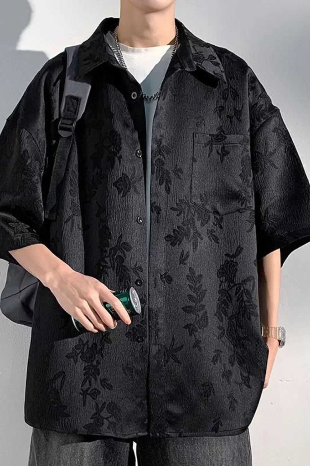 Man wearing oversized black floral textured streetwear shirt, short sleeves, casual style