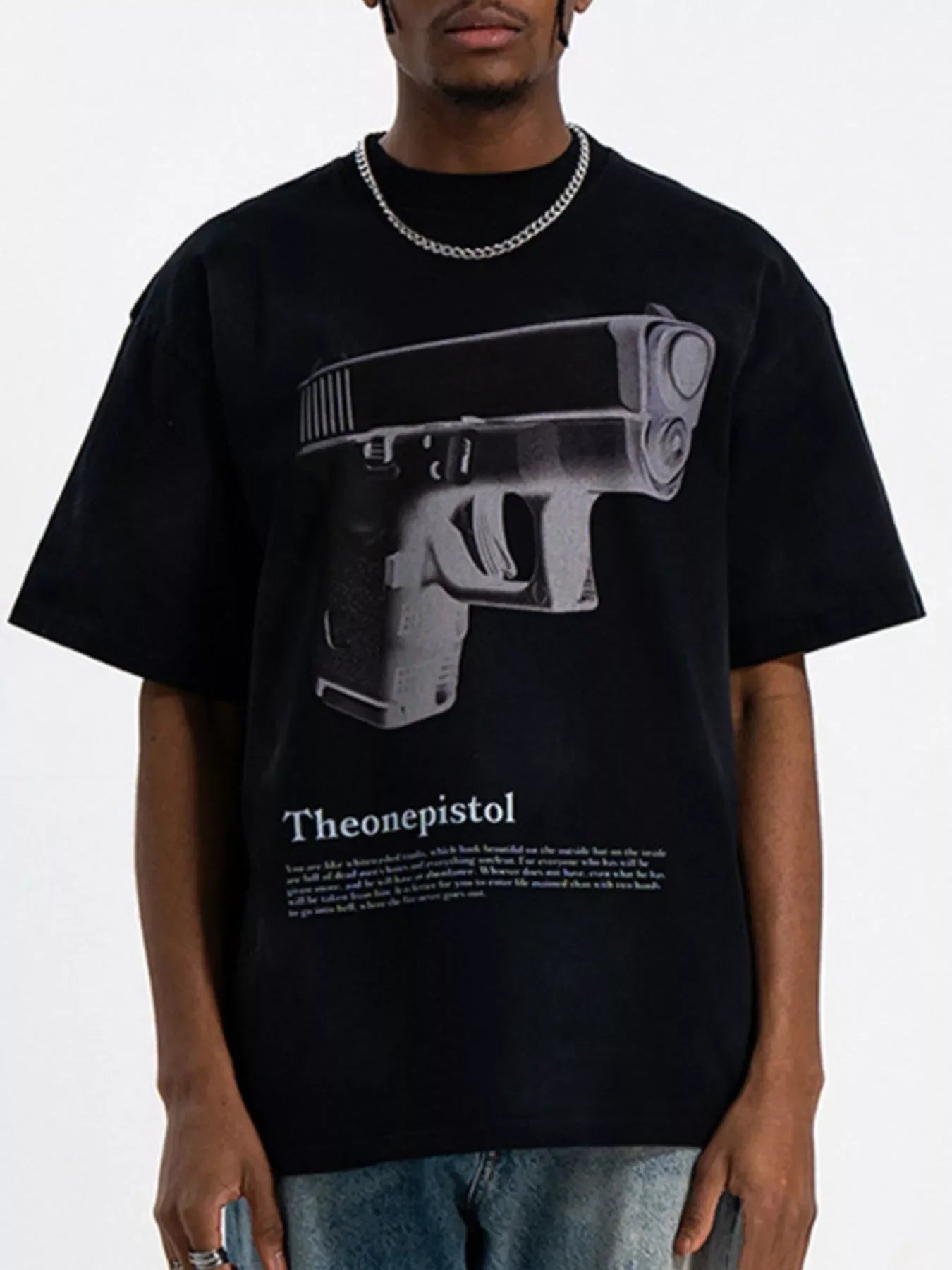 Man wearing oversized black streetwear t-shirt with large pistol graphic and text, urban fashion