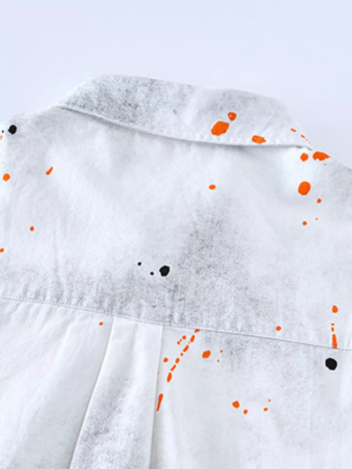 White streetwear shirt back with orange and black paint splatter, urban fashion style