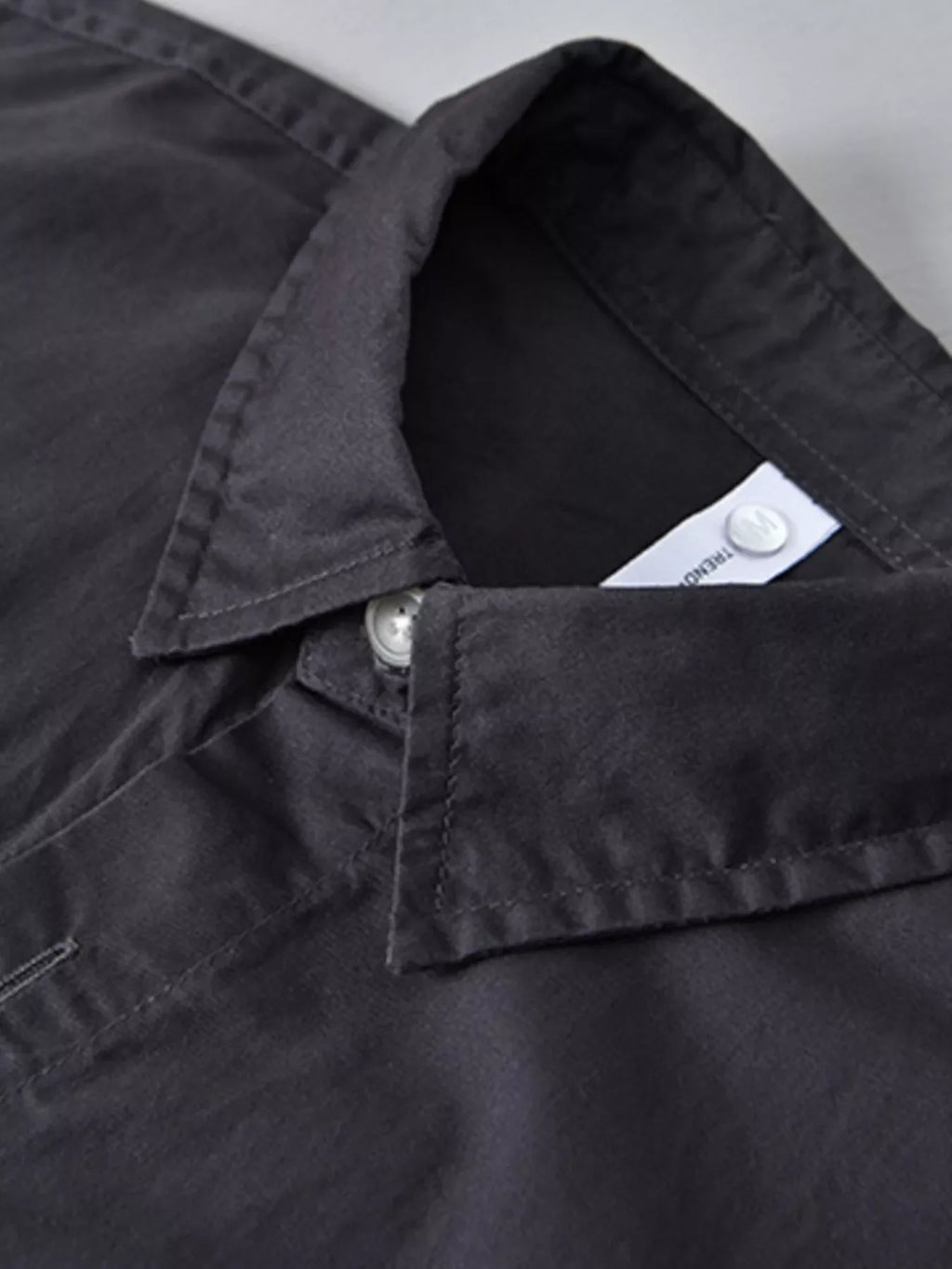Close-up of a black men's streetwear shirt collar, button detail, plus size fashion