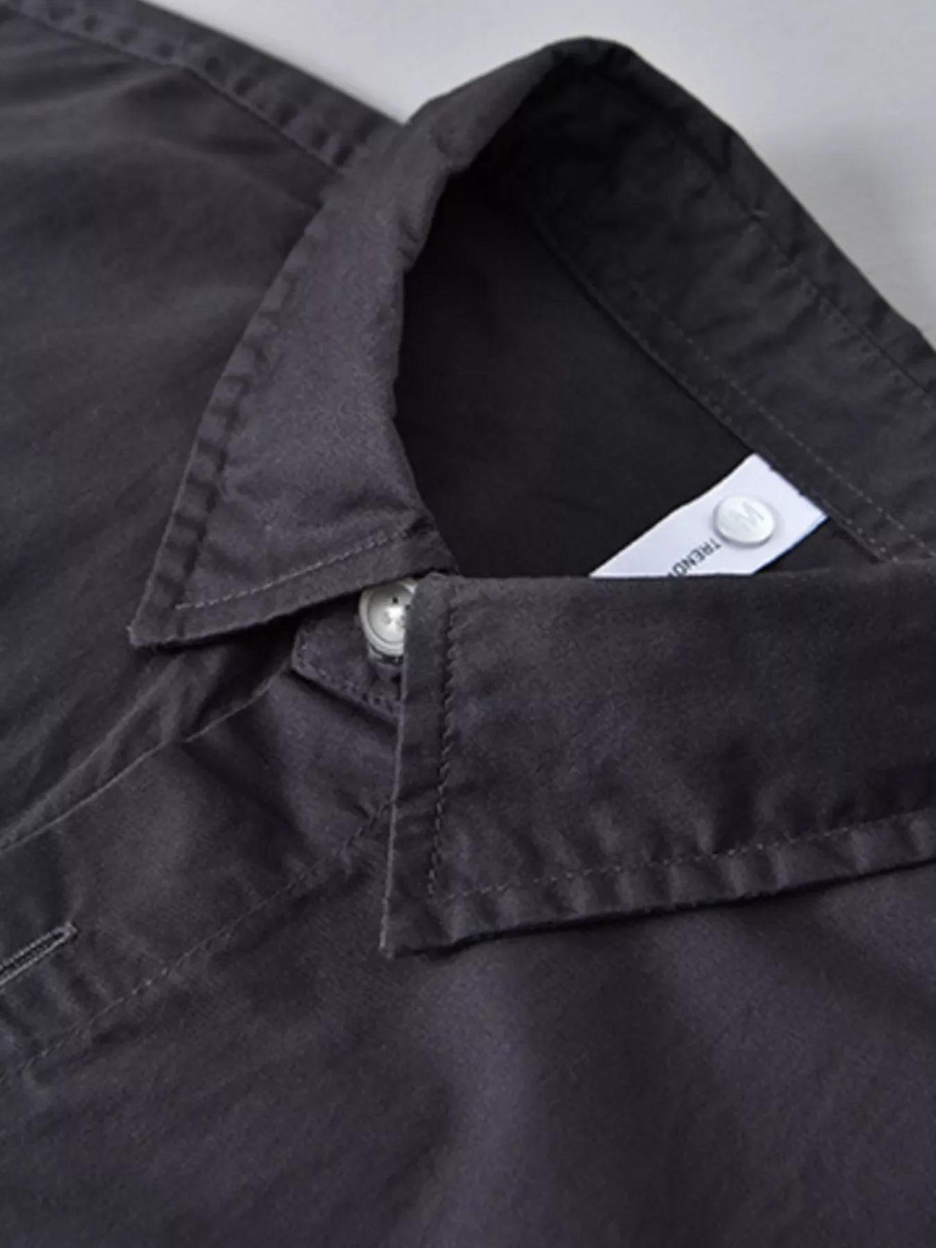Close-up of a black men's streetwear shirt collar, button detail, plus size fashion
