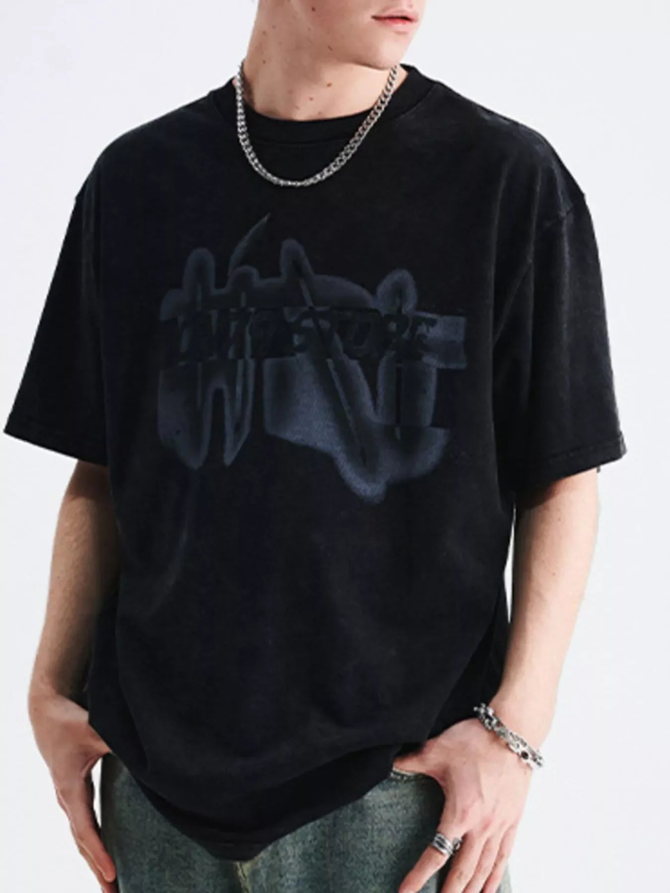 Man wearing oversized black streetwear graphic t-shirt and silver chain, urban style